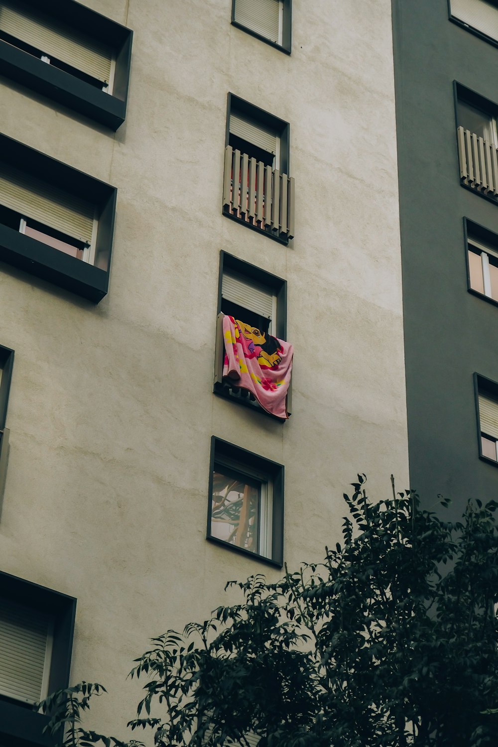 a building with a pink and yellow kite hanging from it's windows