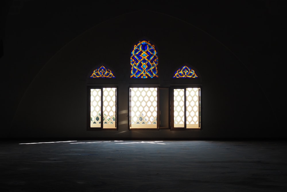 a dark room with three stained glass windows