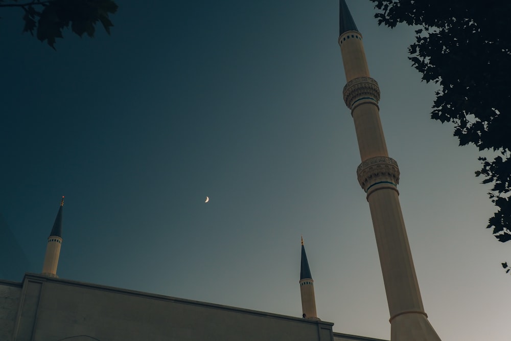 a tall white building with two towers and a moon in the sky