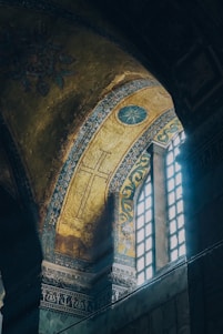 A warm-lit interior of a Syriac Orthodox church featuring intricate crosses and traditional motifs in gold and deep red hues.