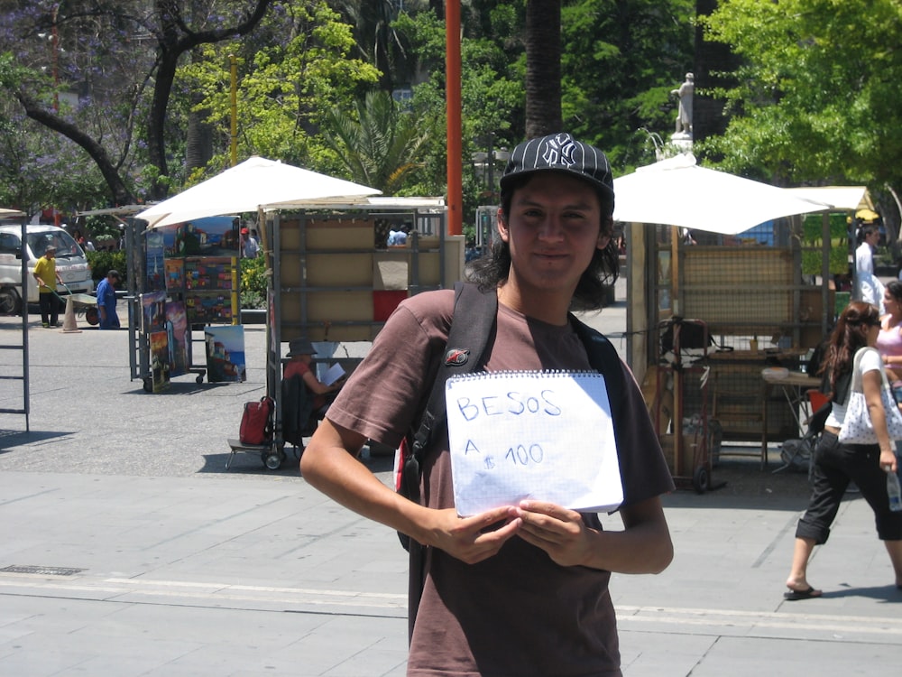 a young man holding a piece of paper with writing on it