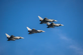 a group of fighter jets flying through a blue sky