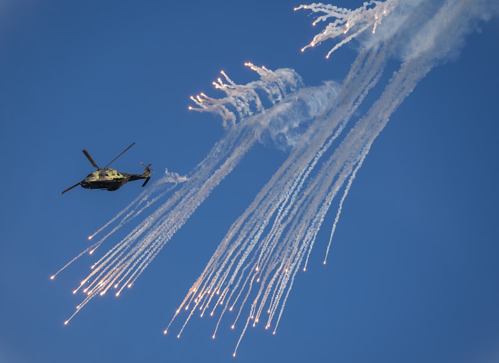 a helicopter flying through a blue sky next to another helicopter