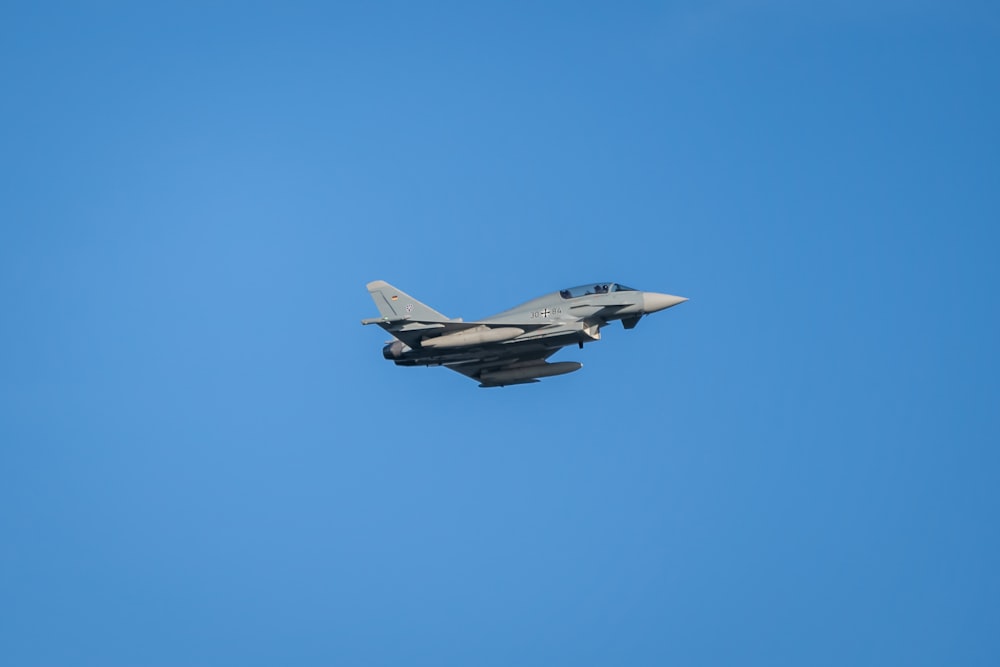 a fighter jet flying through a blue sky