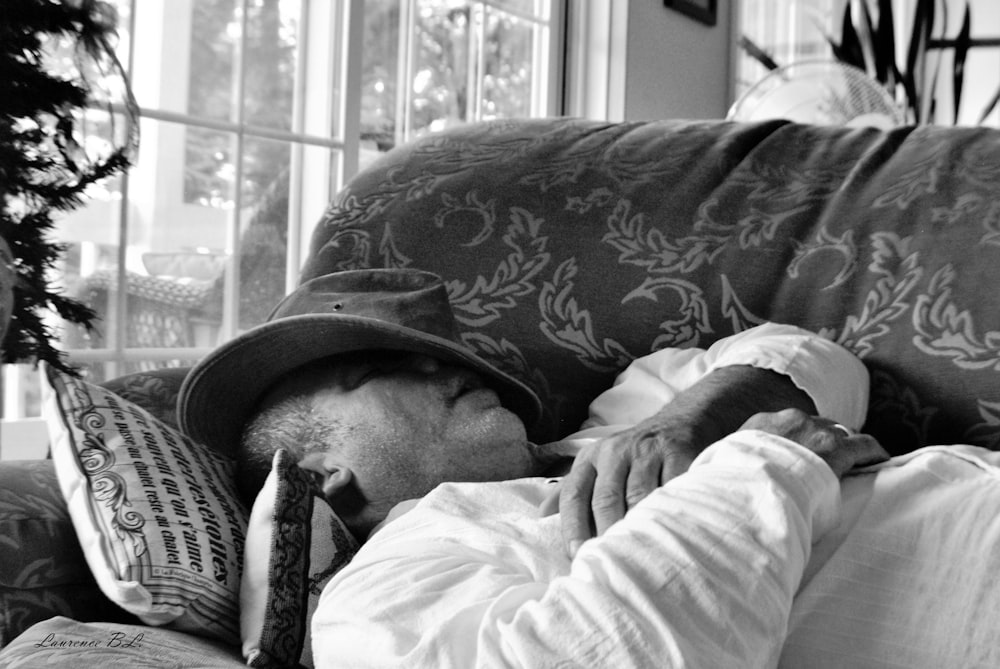 a man sitting on a couch wearing a hat
