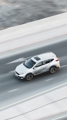 a white car driving down a highway next to a forest