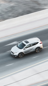 a white car driving down a highway next to a forest