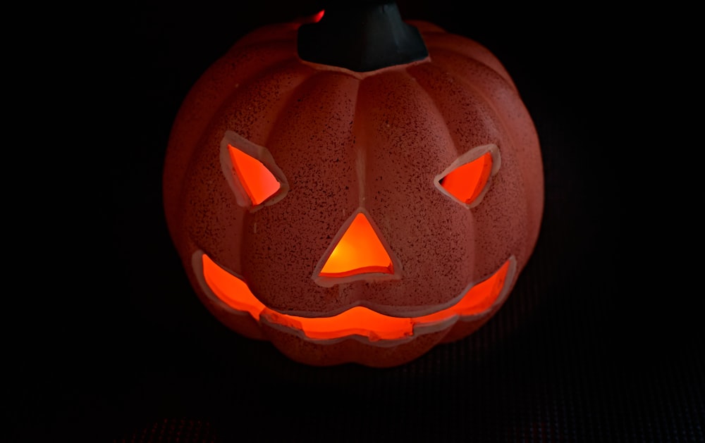 a carved pumpkin with glowing eyes on a black background