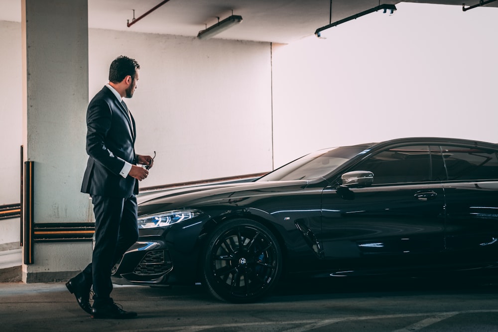 a man in a suit standing next to a car