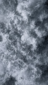 Chaotic and dynamic swirling water with abundant foam and bubbles. The water appears turbulent, suggesting movement and power.