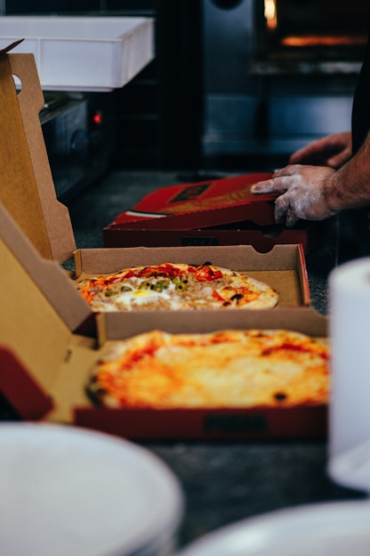 two pizzas in boxes on a table