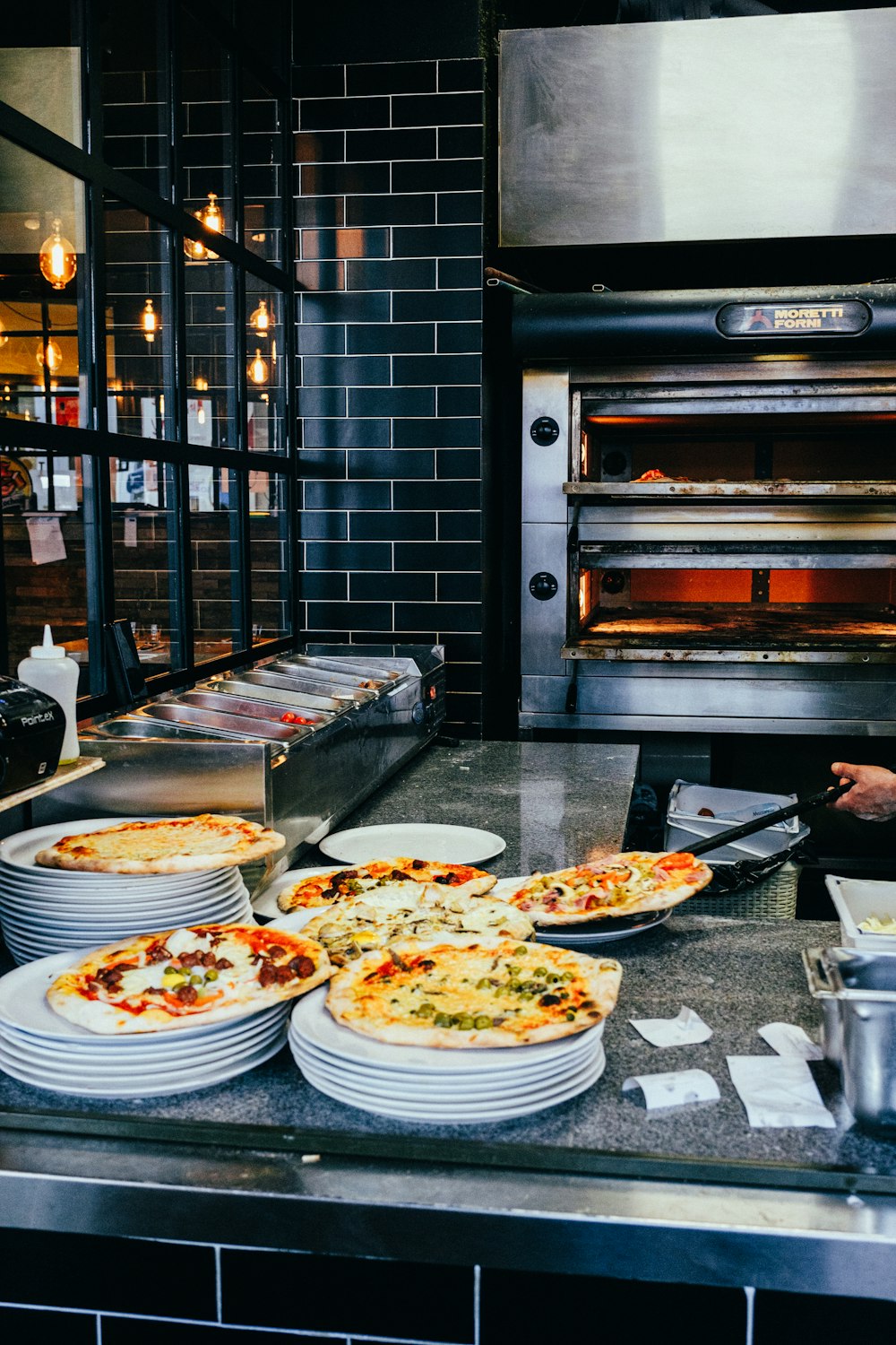 a man in a kitchen preparing pizzas in front of an oven