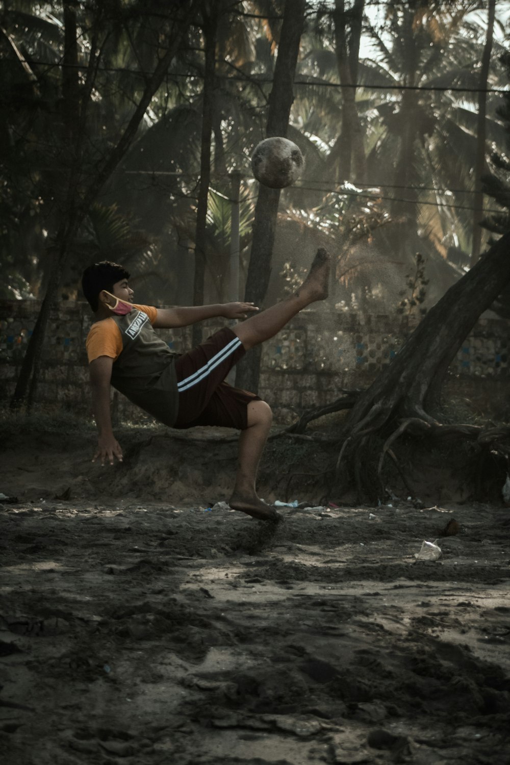 a man kicking a soccer ball in a forest