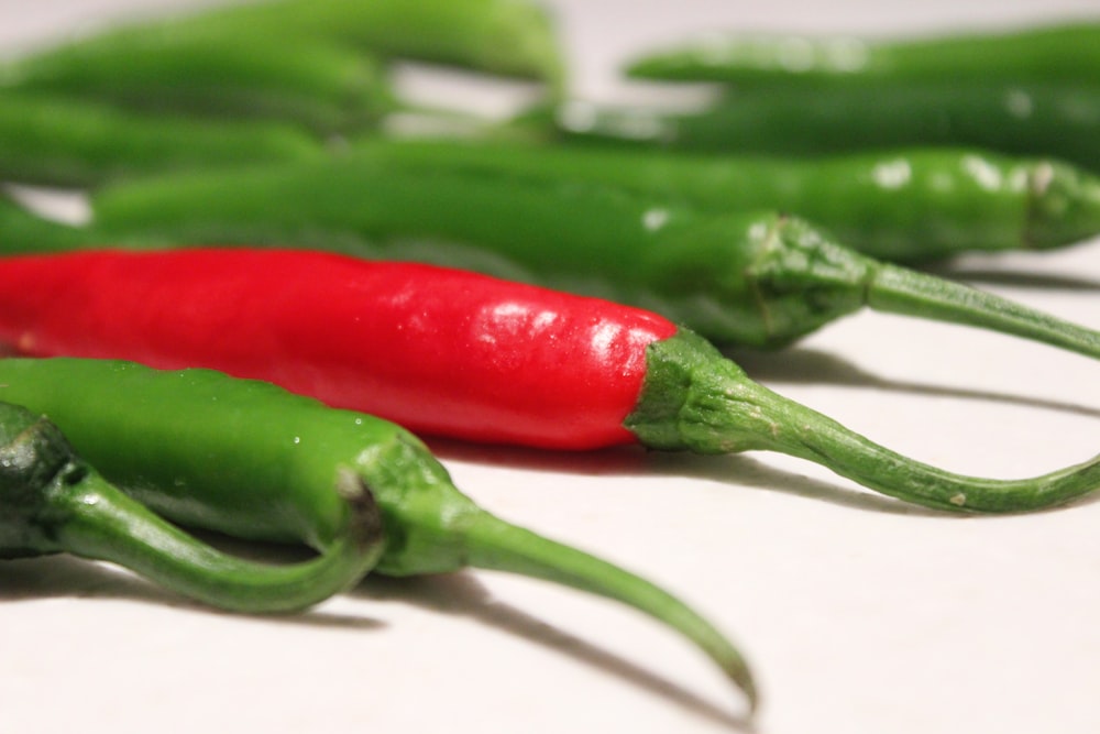 a group of green and red peppers on a table