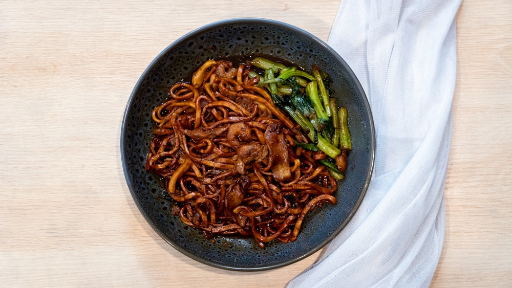 a bowl of noodles and asparagus on a table