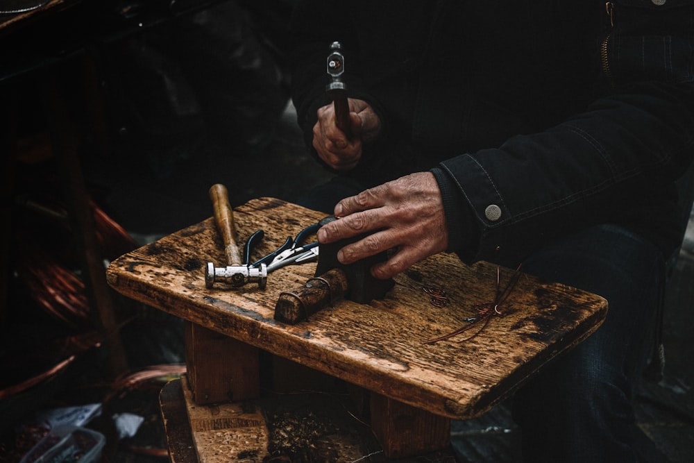 a man is using a pair of scissors to cut a piece of wood