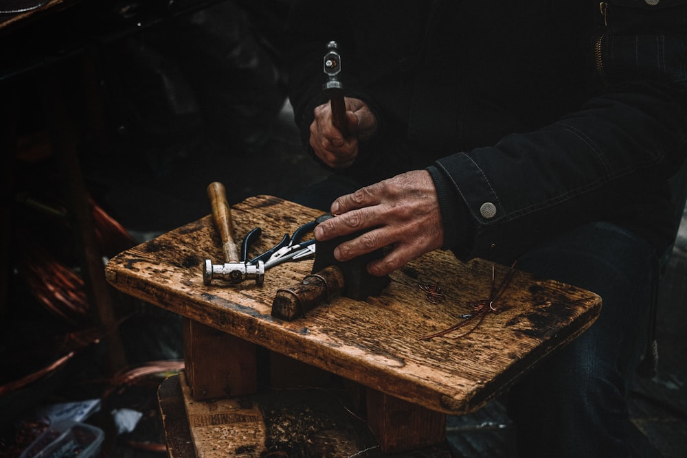 Un hombre está usando un par de tijeras para cortar un trozo de madera
