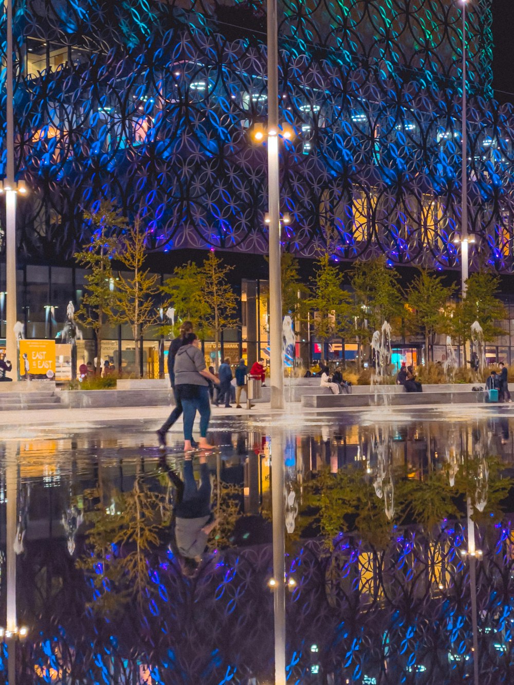 a group of people walking around a city at night