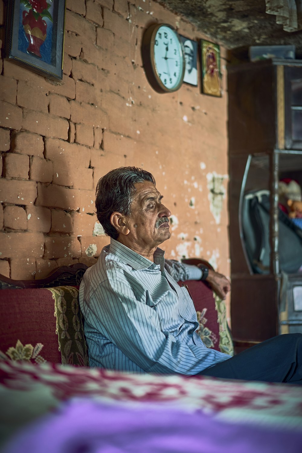 a man sitting on a couch in a room with a brick wall