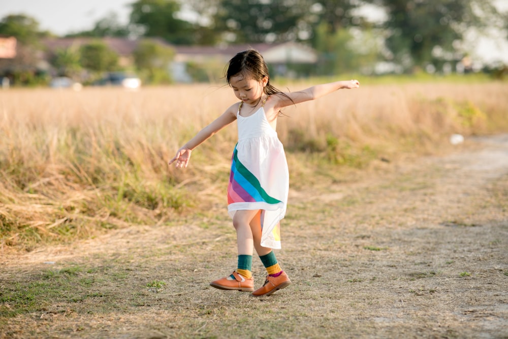 a little girl in a white dress playing with a frisbee