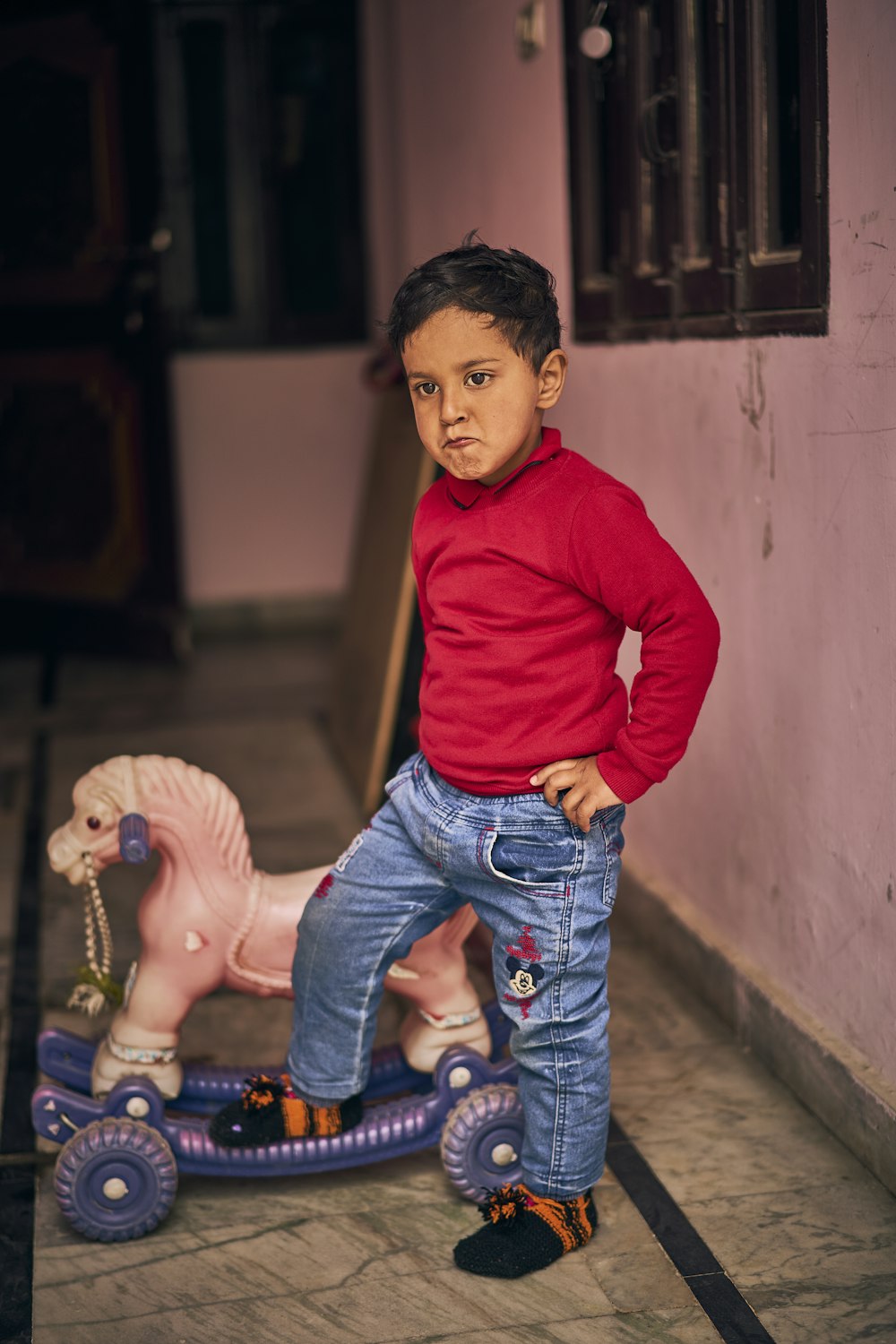 a young boy standing next to a toy horse