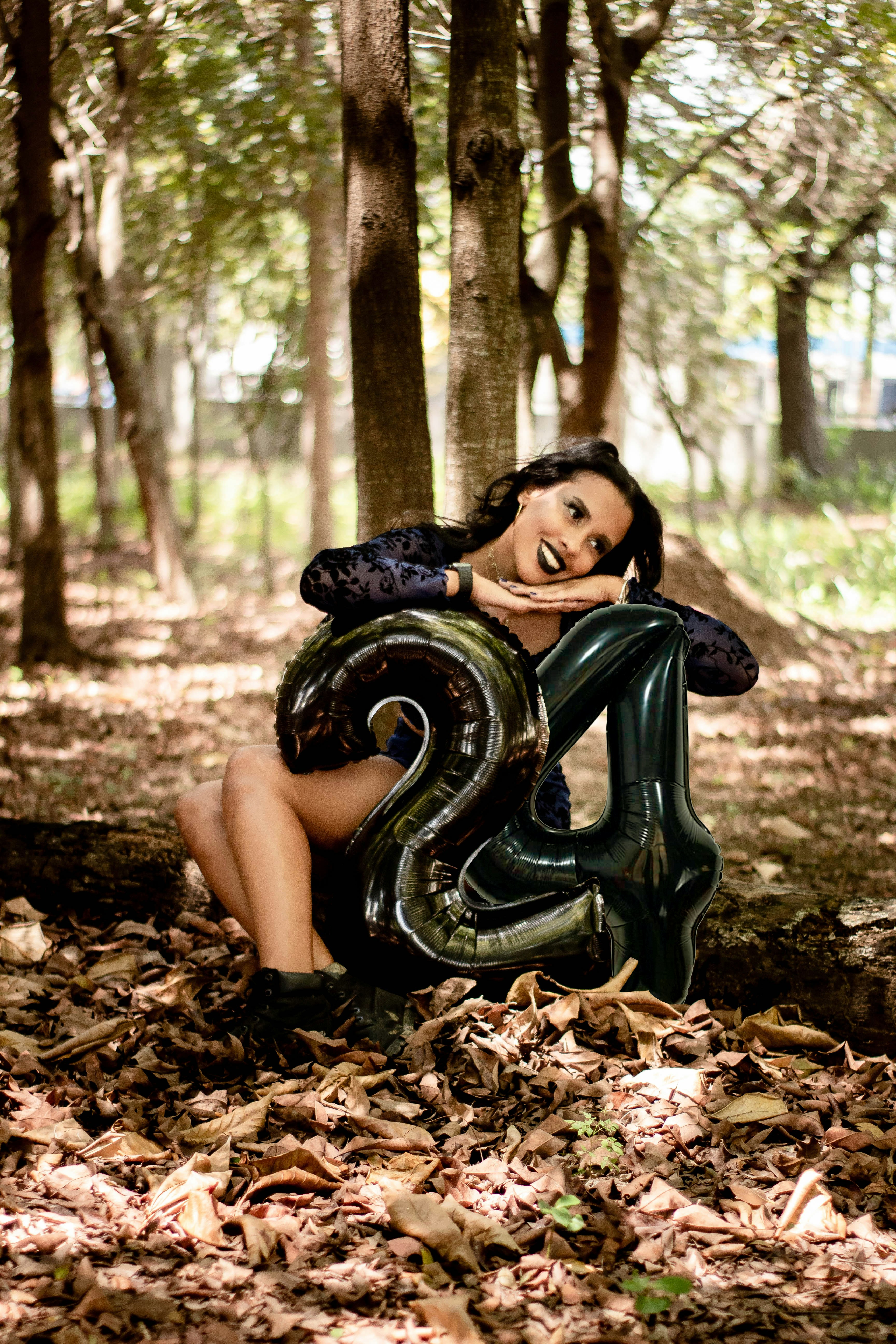 a woman sitting in the woods with a number balloon