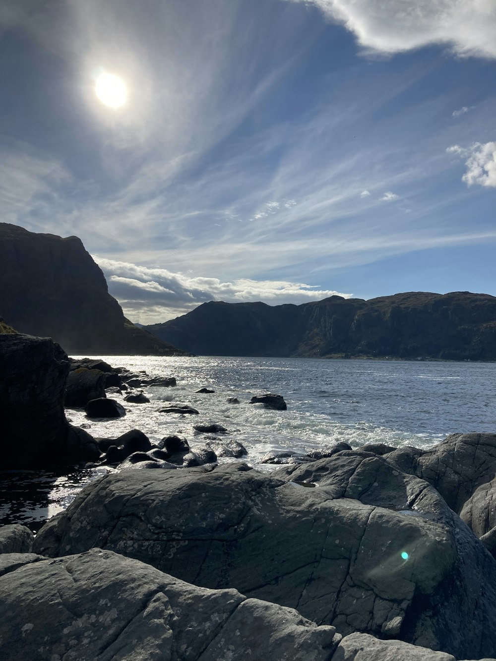 the sun is shining over the water and rocks