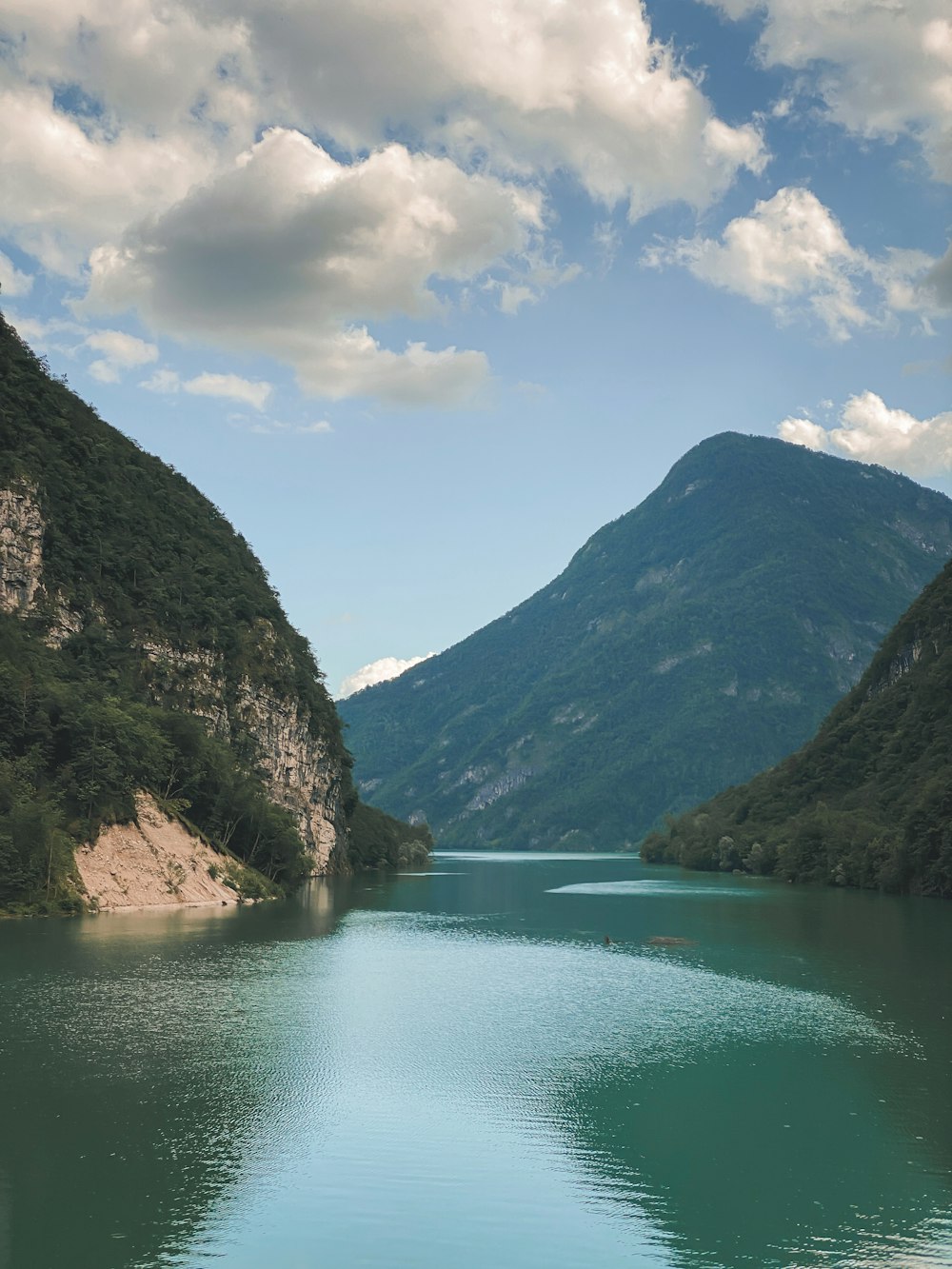 a body of water surrounded by mountains under a cloudy sky