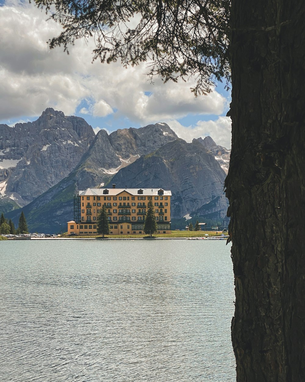 a large building sitting on top of a lake surrounded by mountains