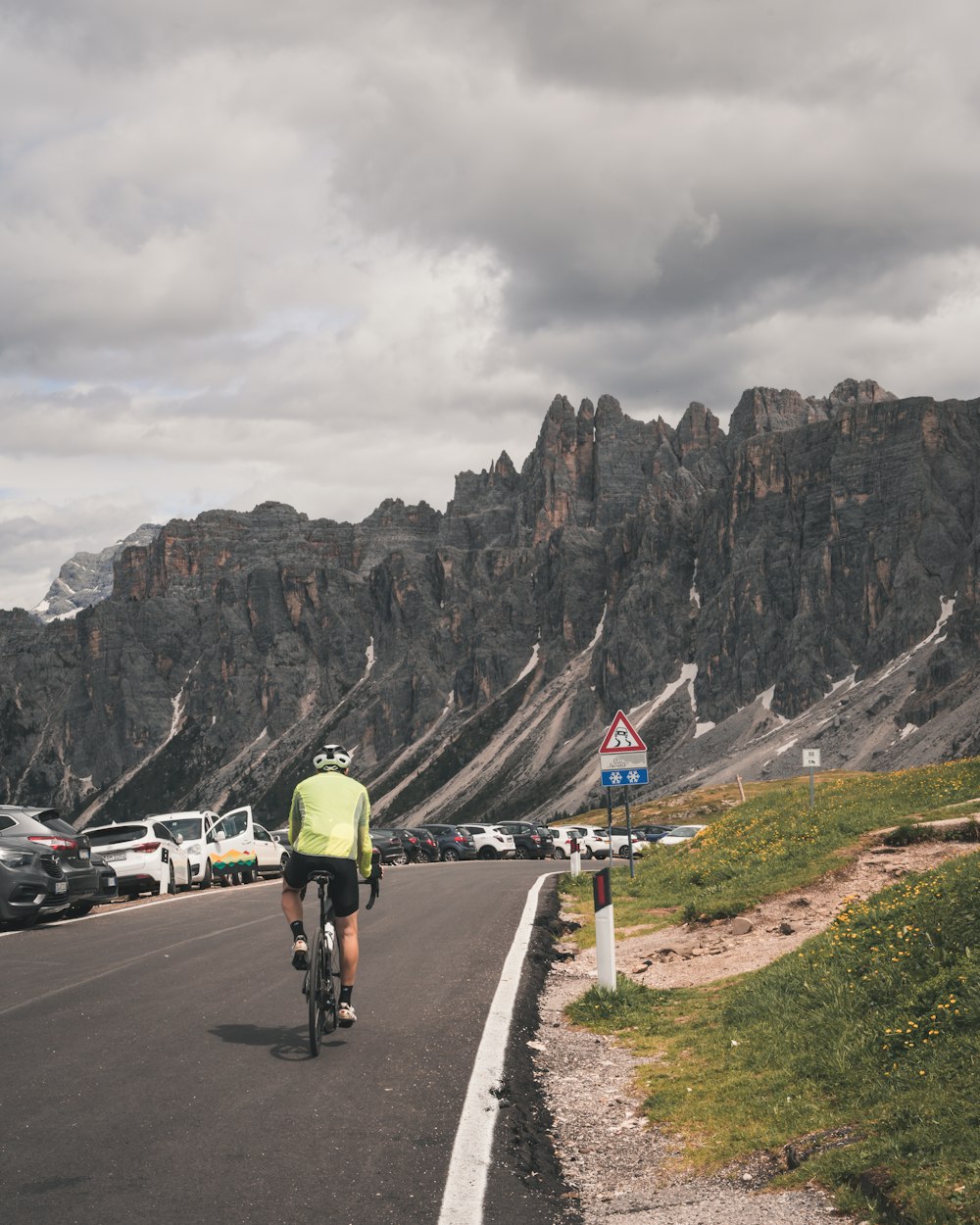 a man riding a bike down a road next to a mountain