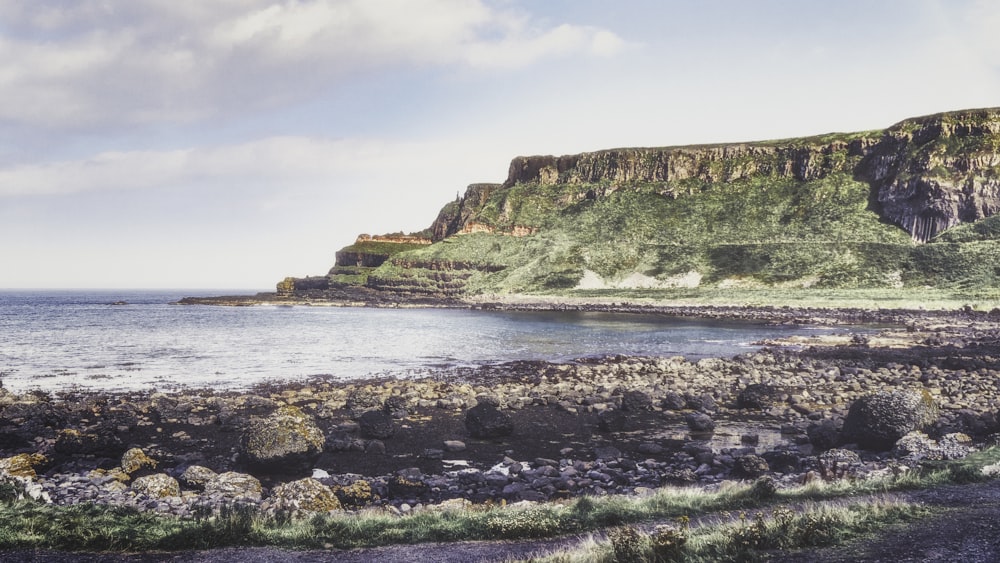 a large body of water sitting next to a lush green hillside