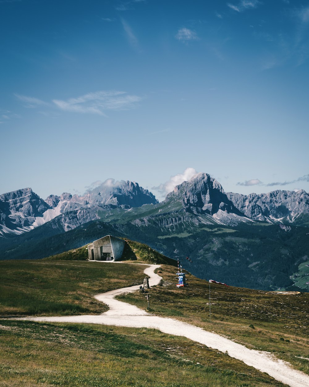 a dirt road going up a hill with mountains in the background