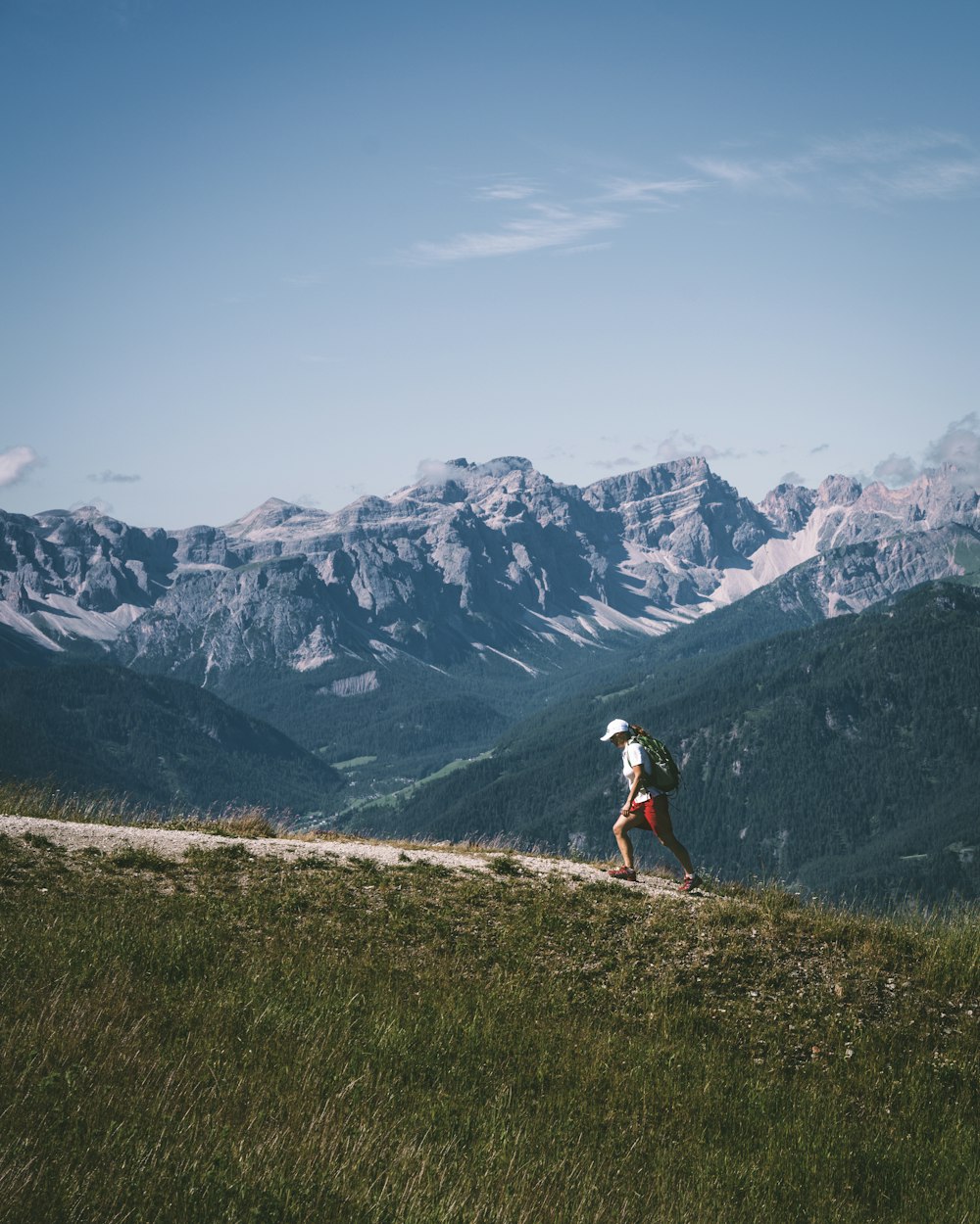 a person hiking up a hill with mountains in the background