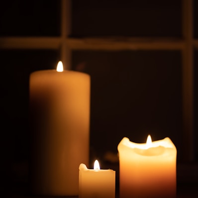 three lit candles sitting on a table in front of a window