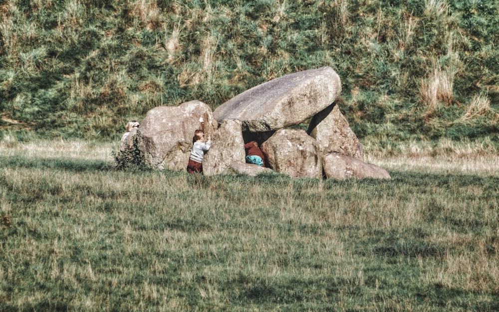 a person standing next to a large rock in a field