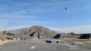 a hot air balloon flying over a pyramid
