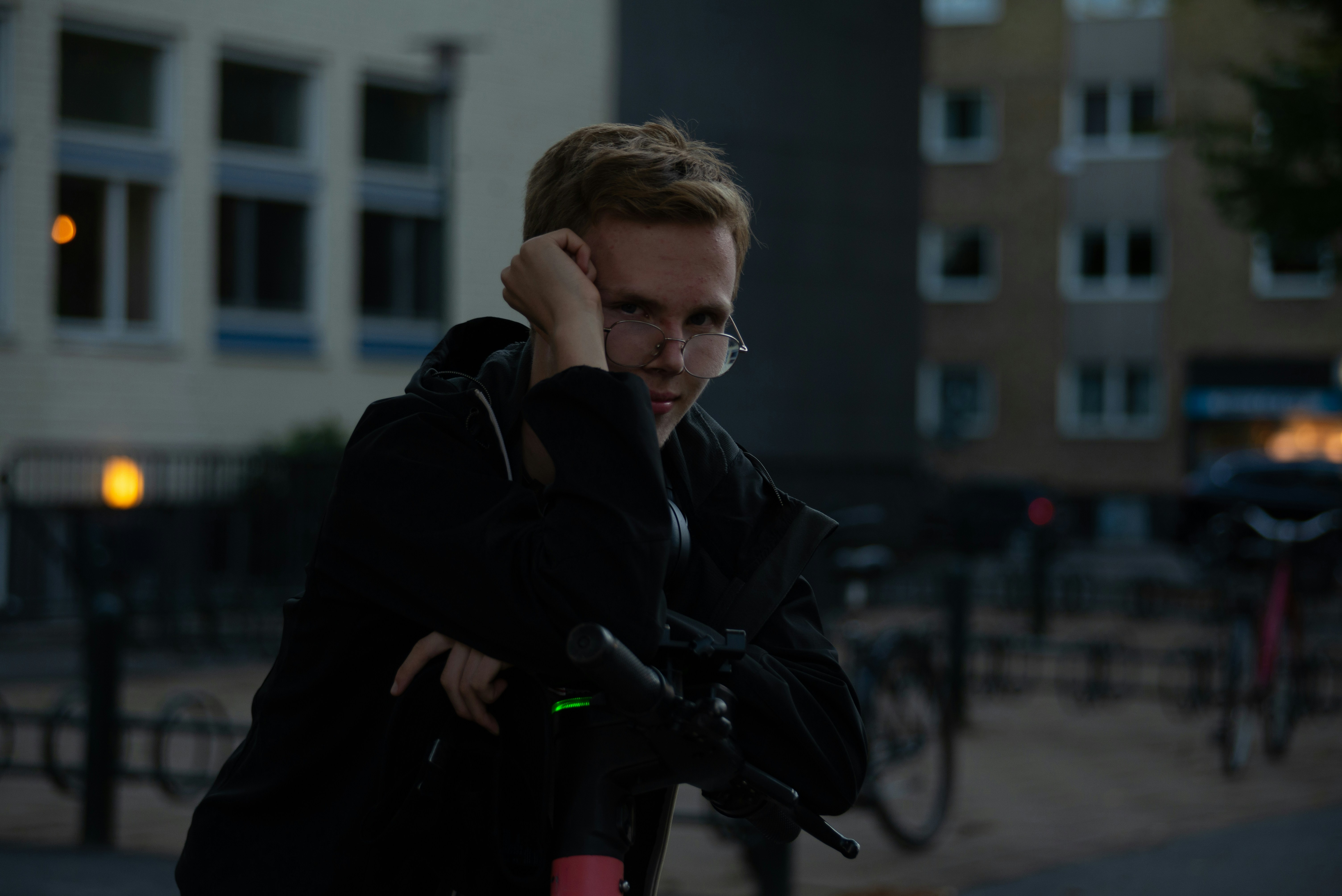 a man in a black jacket is holding a red bike