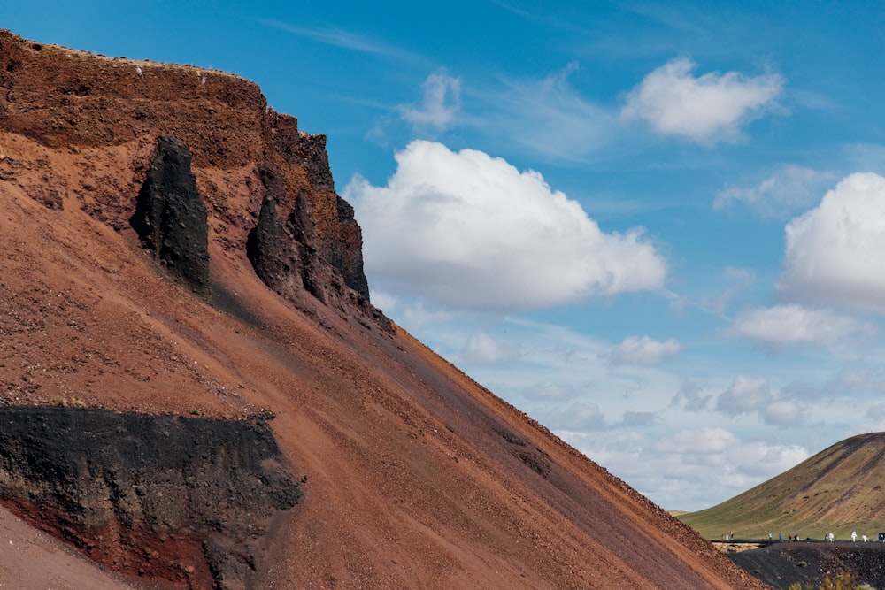 a mountain side with a few clouds in the sky