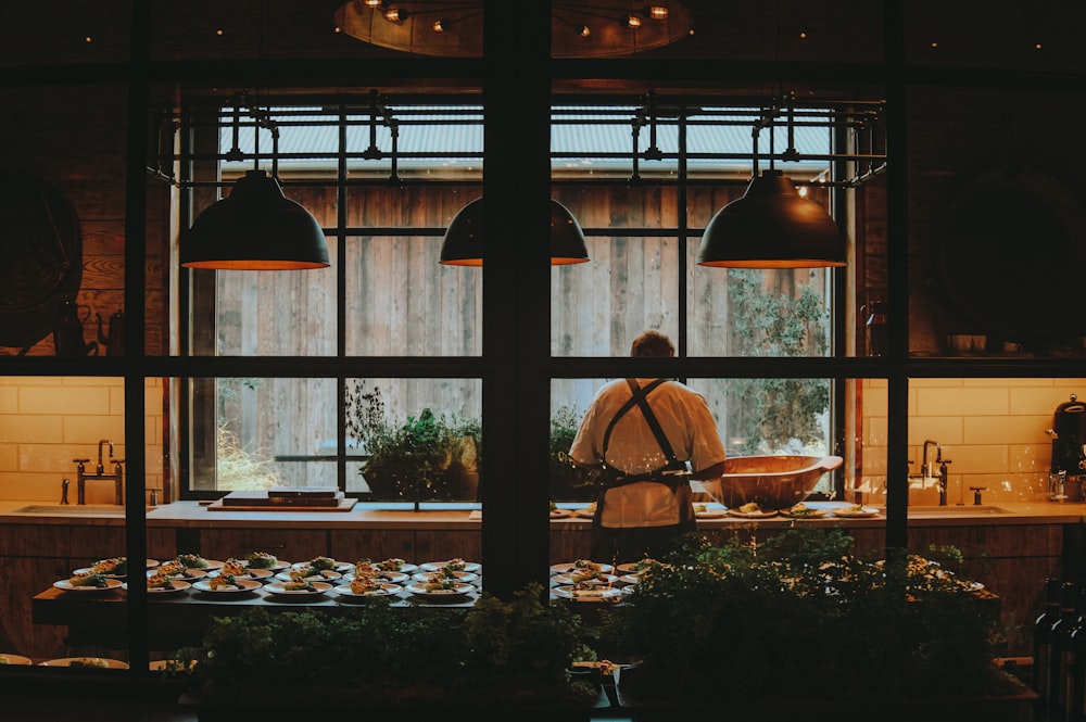 a man standing in front of a window in a kitchen