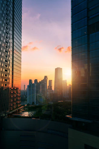 the sun is setting over a city with tall buildings