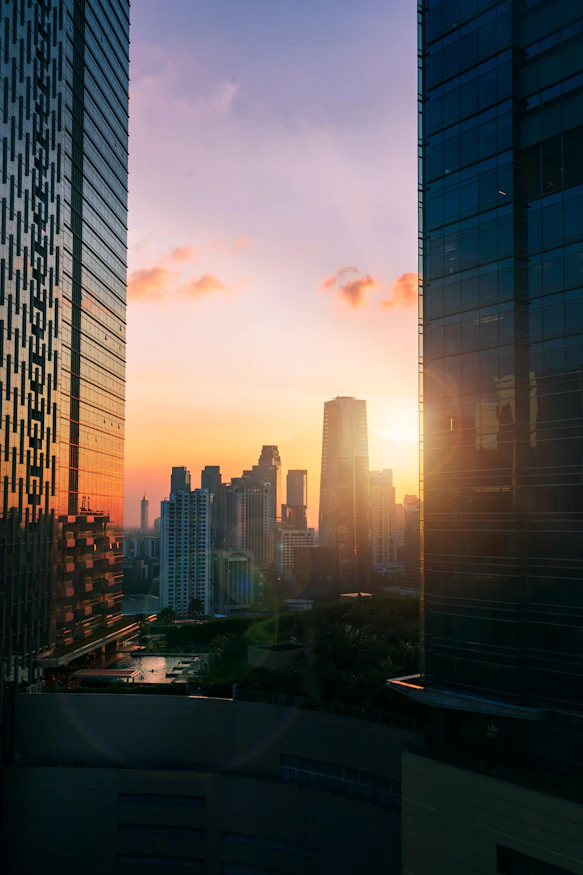 the sun is setting over a city with tall buildings