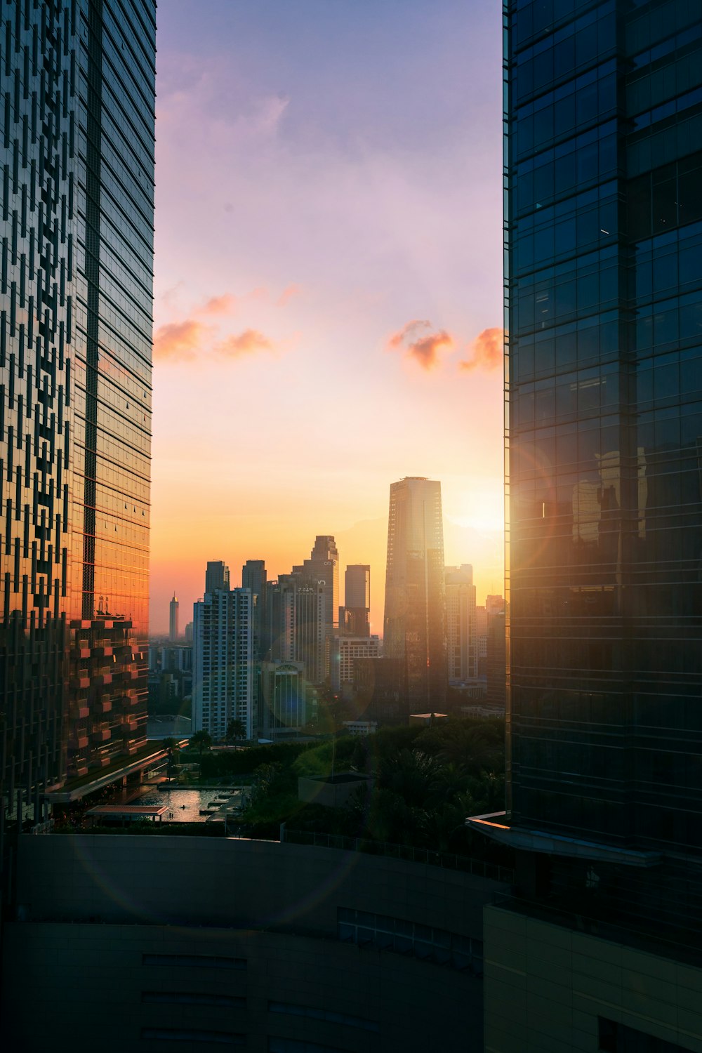 the sun is setting over a city with tall buildings