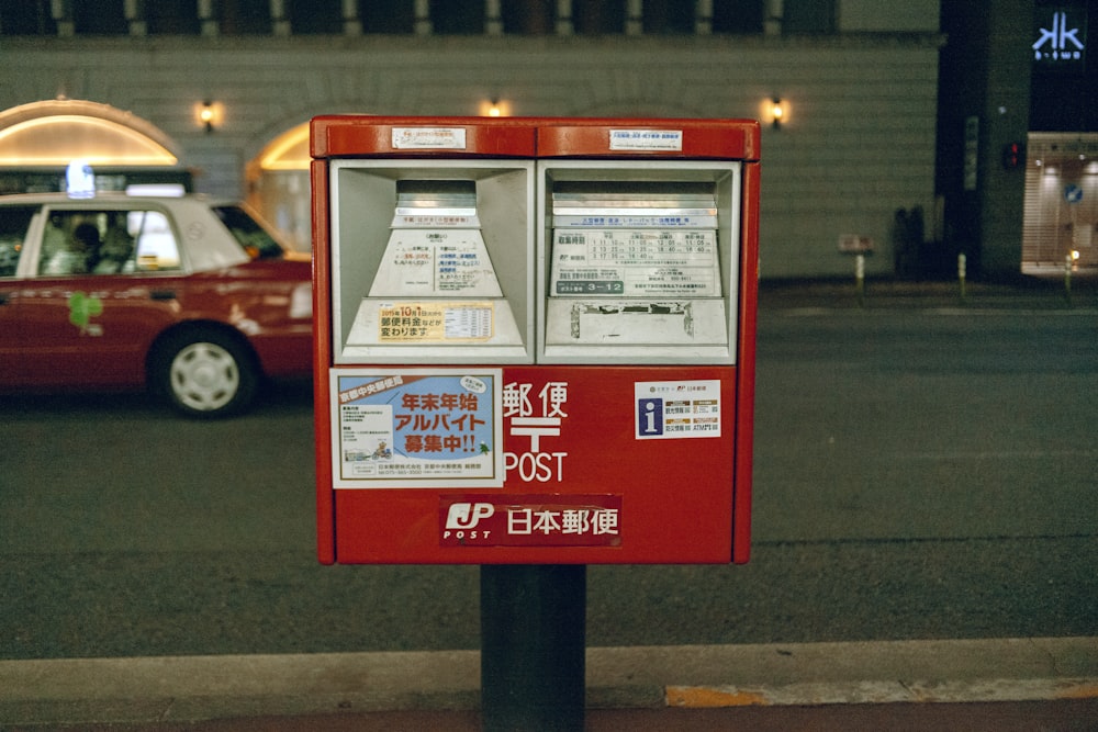 a red parking meter sitting on the side of a road