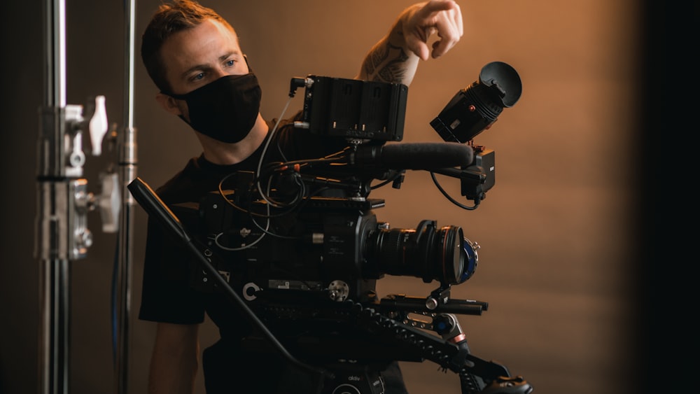 Un uomo che indossa una maschera facciale e tiene in mano una macchina fotografica