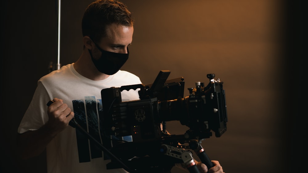 a man wearing a face mask holding a camera