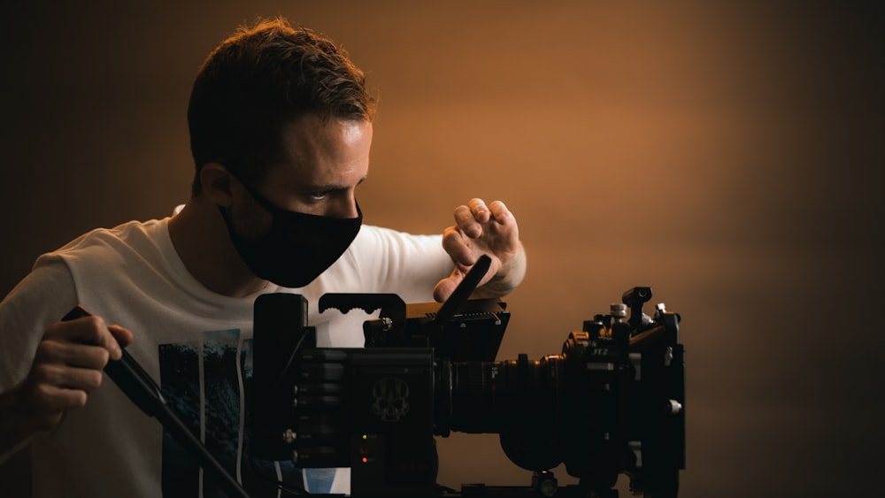 Un uomo che indossa una maschera facciale e tiene in mano una macchina fotografica