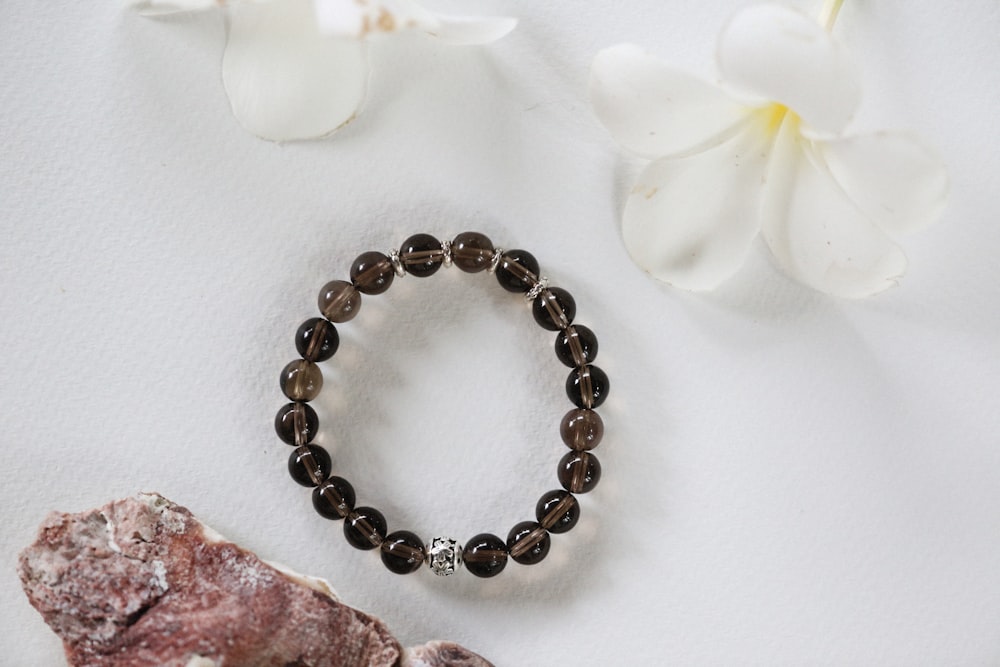 a white flower and a brown beaded bracelet