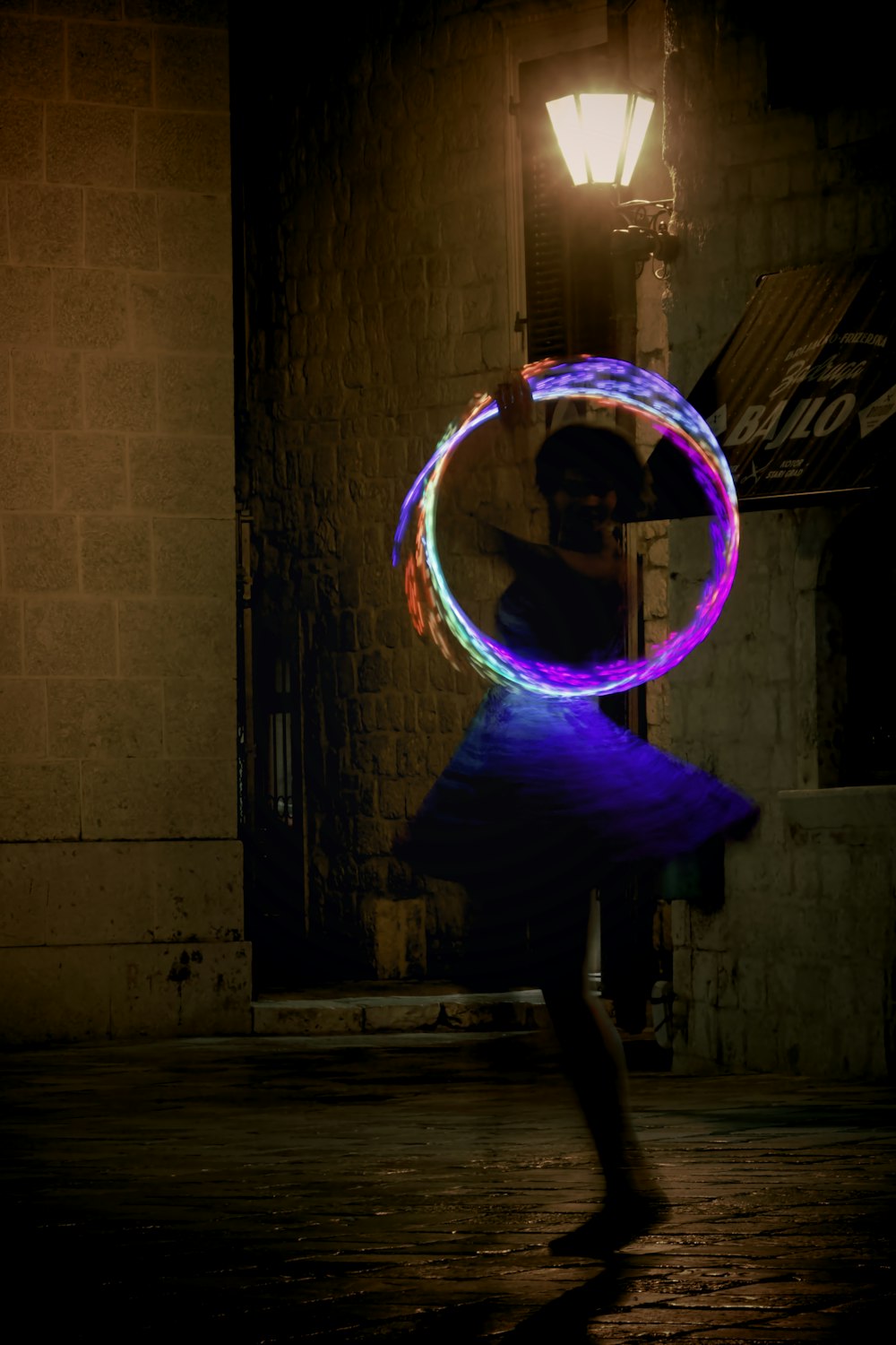 a woman holding a lit hula hoop in the dark