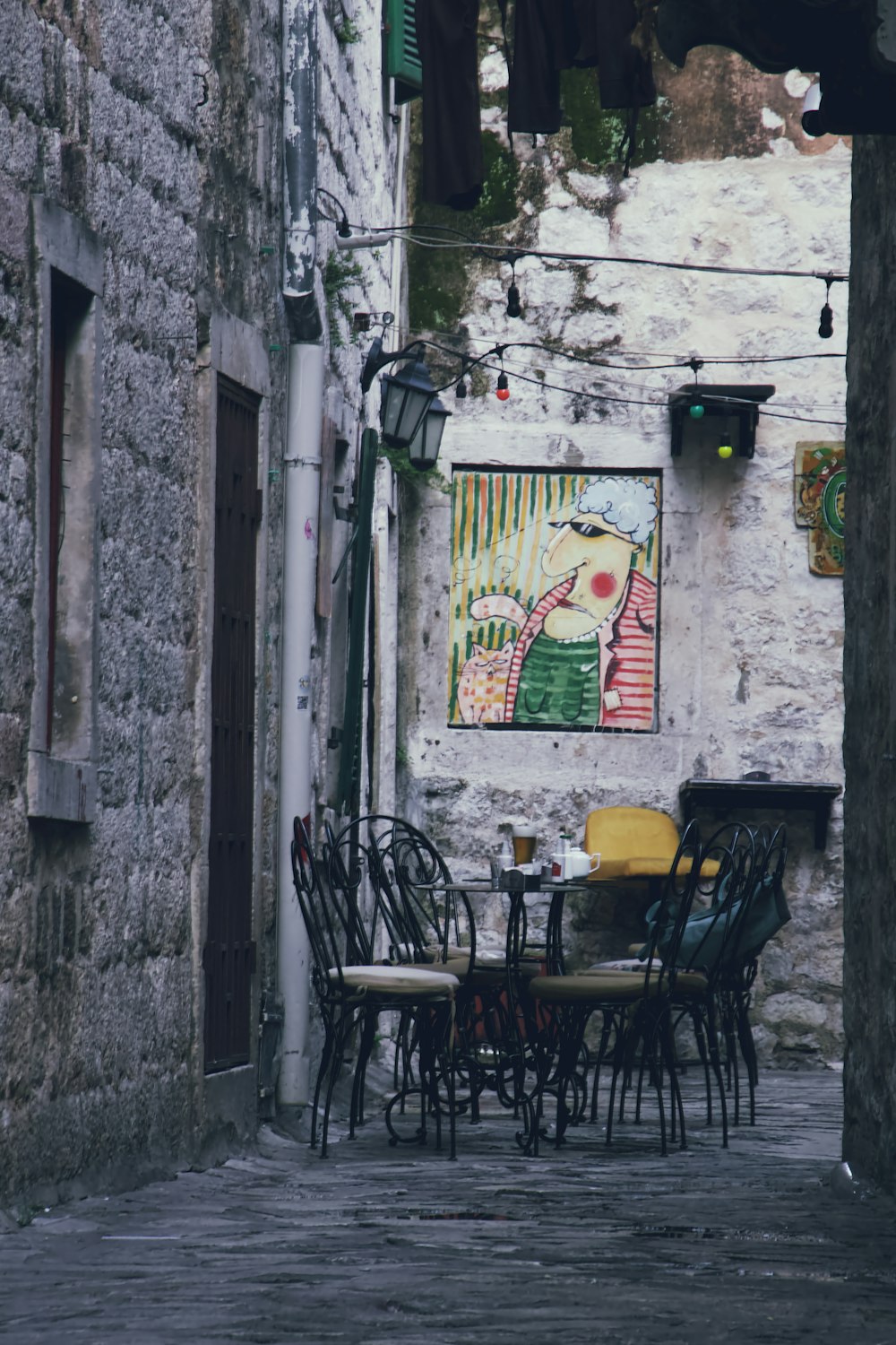 an alleyway with tables and chairs and a painting on the wall