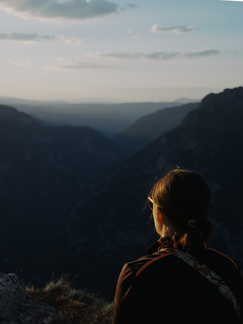Eine Frau sitzt auf einem Berg mit Blick auf ein Tal